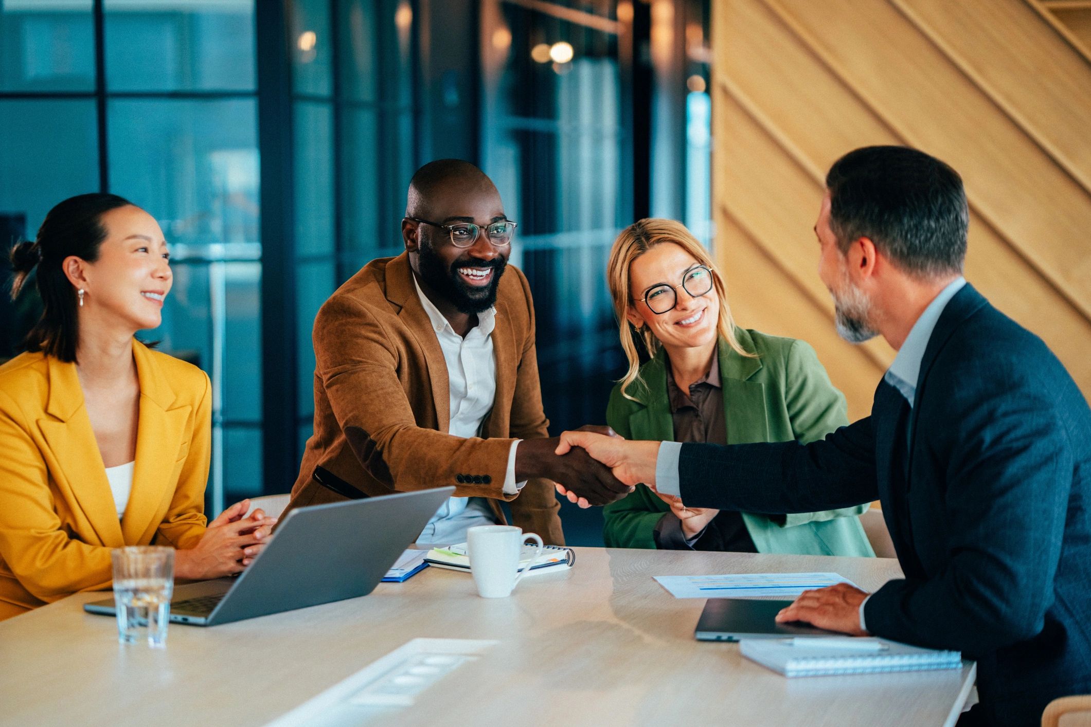 Business professionals shaking hands at a conference table
